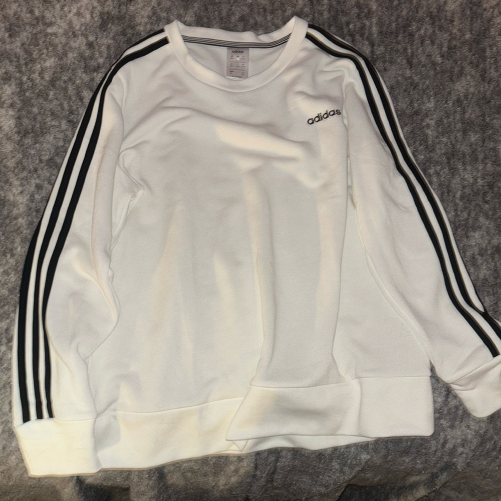 It’s a white crew neck from adidas. It has 3 black lines on the side.